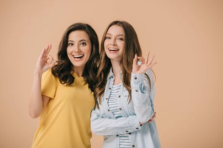 attractive and smiling friends showing okay isolated on beige