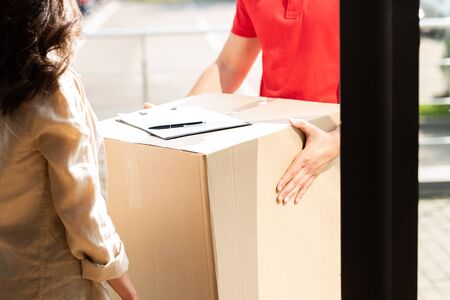 cropped view of delivery man holding box near woman 