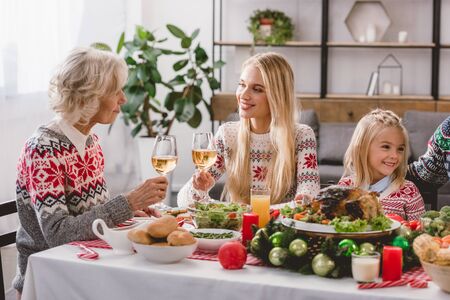 family members sitting at table and holding wine glasses in Christmasの写真素材