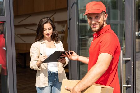 handsome delivery man holding clipboard near attractive girlの写真素材