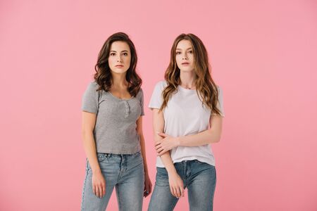 attractive women in t-shirts looking at camera isolated on pink