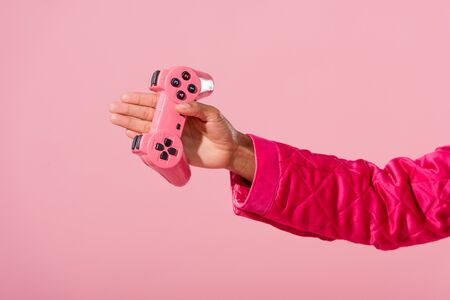 KYIV, UKRAINE - SEPTEMBER 16, 2019: cropped view of african american woman holding joystick isolated on pink, fashion doll conceptの写真素材