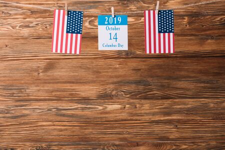 calendar  with 14 October date between American national flags on wooden surface
