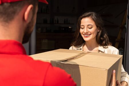 selective focus of positive girl taking box near delivery man