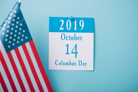 paper calendar with Columbus Day inscription near American national flag on blue backgroundの写真素材