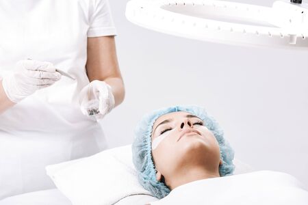 eyelash master taking false eyelashes with tweezers near model face isolated on whiteの写真素材