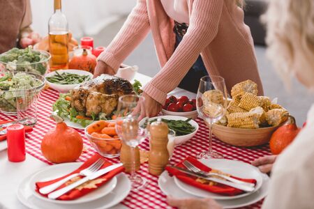 cropped view of mother putting on table plate with turkey in Thanksgiving dayの写真素材