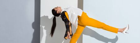 panoramic shot of happy girl posing while standing on grey and white の写真素材