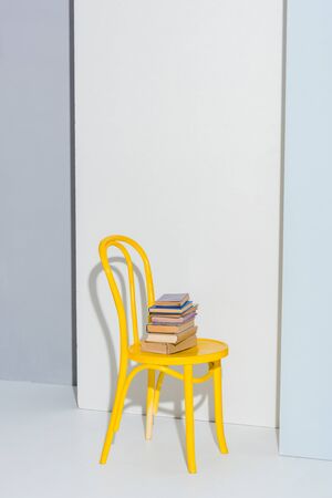 yellow chair with books on white and grey の写真素材