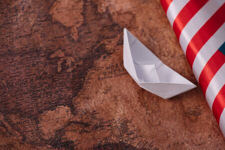 white paper boat near American national flag on ancient world mapの写真素材