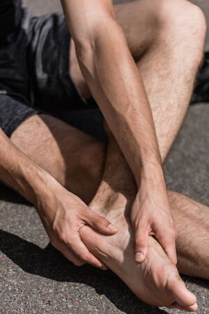 partial view of barefoot sportsman with foot pain on street