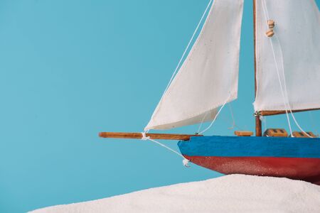 close up view of decorative ship in white sand isolated on blue