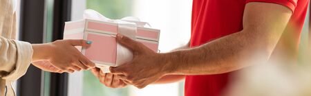 panoramic shot of delivery man giving pink present to woman の写真素材