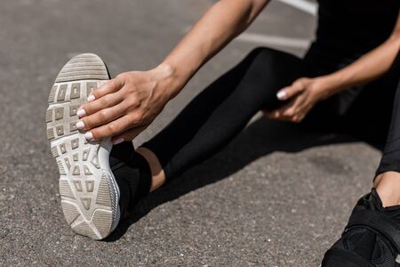 partial view of sportswoman with leg pain stretching on streetの写真素材