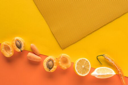 top view of fresh fruits and vegetables on yellow and orange background with copy spaceの写真素材