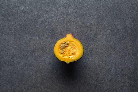 top view of yellow pumpkin on grey textured background with copy space
