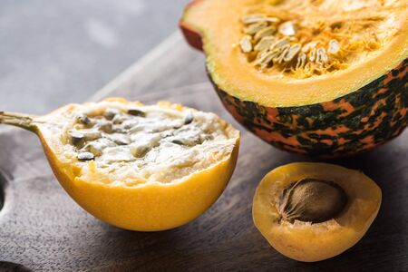 close up view of yellow sweet granadilla, pumpkin and apricot on wooden chopping boardsの写真素材