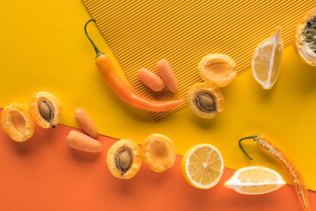 top view of fresh fruits and vegetables on yellow and orange background with copy spaceの写真素材