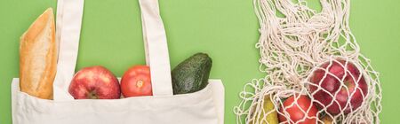 top view of fresh baguette, vegetables and fruits in cotton and string bag isolated on green, panoramic shotの写真素材
