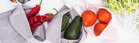 top view of fresh avocados, tomatoes and chili peppers in eco friendly bags isolated on white,...