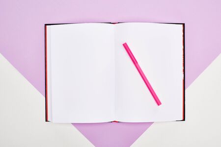 top view of open empty notebook with felt pen on violet and white backgroundの写真素材