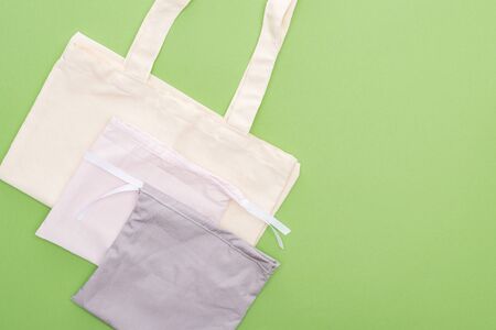 top view of empty cotton eco bags isolated on greenの写真素材