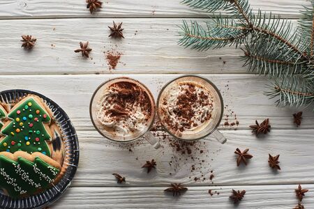 top view of cacao in mugs on white wooden table with fir branch, anise and Christmas cookiesの写真素材
