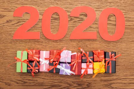 top view of paper 2020 numbers near small decorative gift boxes on wooden background