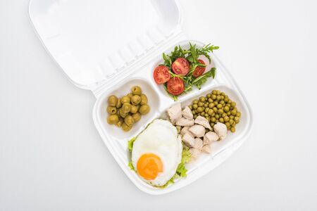 top view of eco package with vegetables, meat, fried egg and salad on white backgroundの写真素材