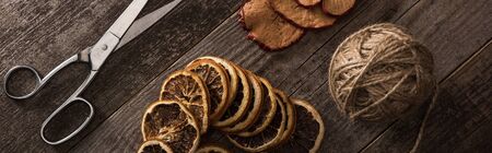 top view of thread, scissors and dried citrus and apple slices on wooden background, panoramic shotの写真素材