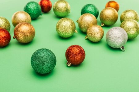 selective focus of multicolored Christmas baubles on green backgroundの写真素材