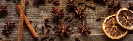 top view of cinnamon sticks, anise and dried citrus fruit on wooden rustic table, panoramic shotの写真素材