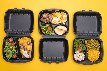 top view of eco packages with apples, vegetables, meat, fried eggs and salads isolated on yellowの写真素材