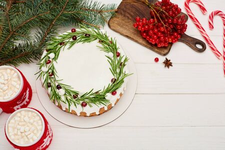 top view of christmas pie on white wooden table with candy canes, cocoa, viburnum berries and spruce branchesの写真素材
