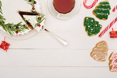 top view of christmas pie, cup of tea and christmas tree cookies on white wooden tableの写真素材