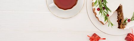 top view of christmas pie with rosemary and cranberries on white wooden table with cup of tea little giftsの写真素材