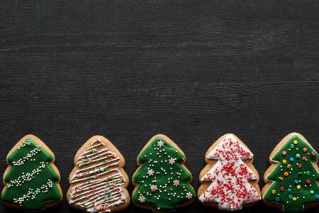flat lay with delicious glazed Christmas tree cookies on black background with copy spaceの写真素材