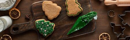 top view of glazed Christmas cookies with pastry bag on wooden table, panoramic shot
