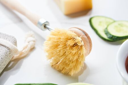 close up view of body brush near cucumber slices on white surfaceの写真素材