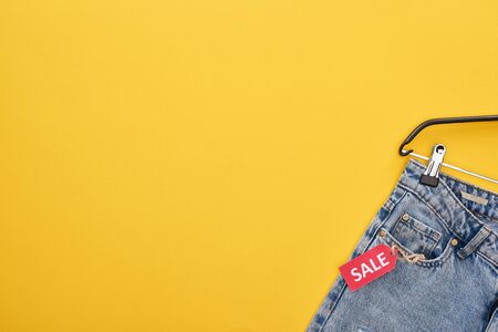 top view of fashionable jeans with sale label on yellow backgroundの写真素材
