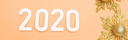 top view of white 2020 numbers near golden christmas decoration on orange background, panoramic shot