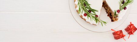 top view of christmas pie with rosemary and red berries on white wooden table with little giftsの写真素材