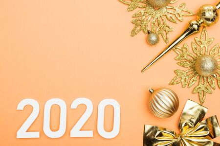 top view of white 2020 numbers near golden christmas decoration on orange backgroundの写真素材
