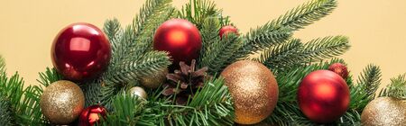 top view of christmas tree branch with baubles on yellow background, panoramic shot