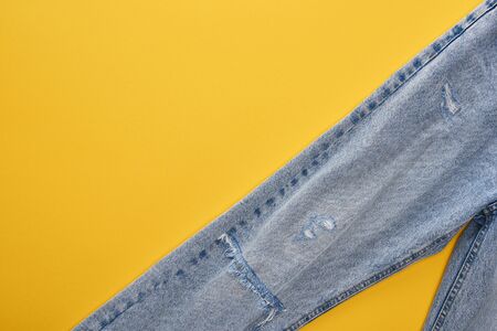top view of fashionable jeans on yellow background