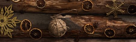 top view of anise, dried citrus slices, ball of thread and snowflakes on wooden background,...