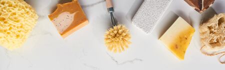 panoramic shot of bath sponge, pumice stone, body brush, soap on marble surfaceの写真素材