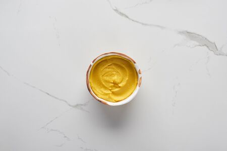 top view of autumnal mashed pumpkin soup in bowl on marble surfaceの写真素材