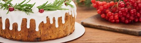 close up of christmas pie with rosemary and viburnum berries on wooden table with spruce branches