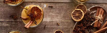 top view of traditional warm pear mulled wine with spices and dried citrus on wooden rustic table, panoramic shotの写真素材